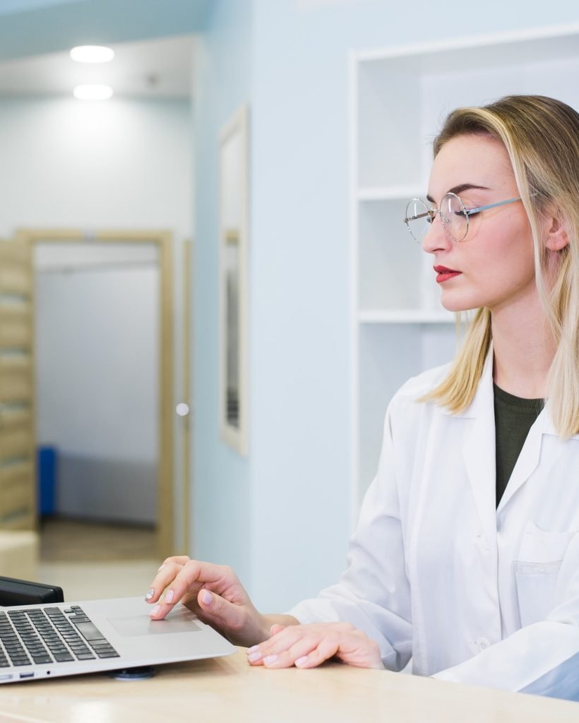 smiling-nurse-with-laptop-scheduling-appointment-for-male-patient-at-reception.jpg